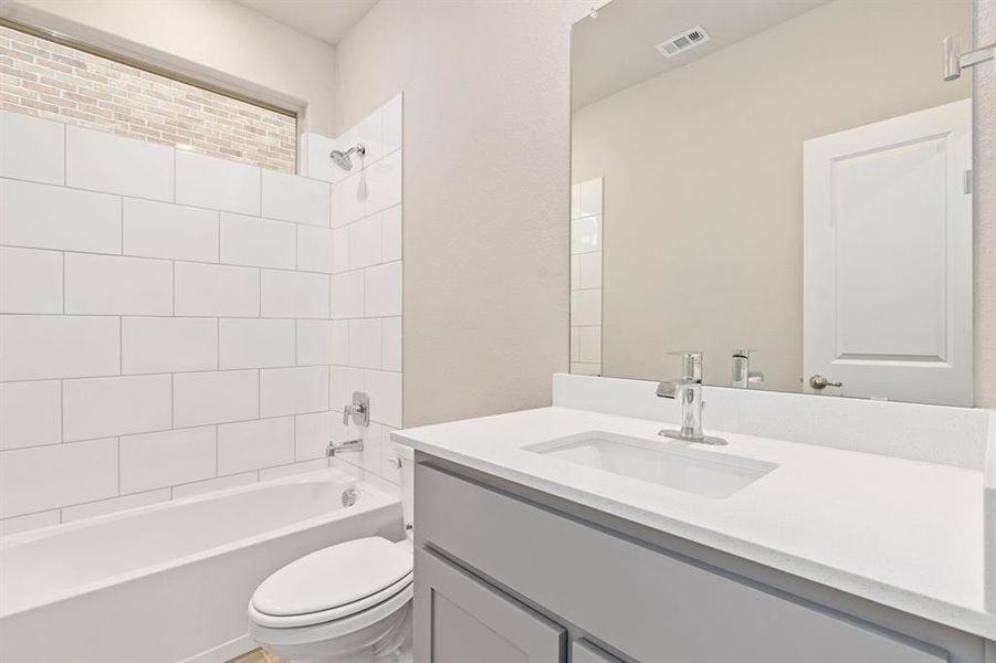 Full bathroom featuring vanity, toilet, and tiled shower / bath combo