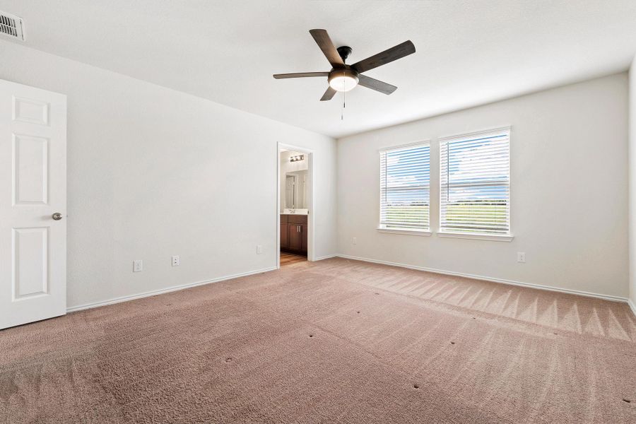A spacious primary bedroom with a ceiling fan offers comfort and direct access to a private bath. A spacious primary bedroom with a ceiling fan offers comfort and direct access to a private bath.