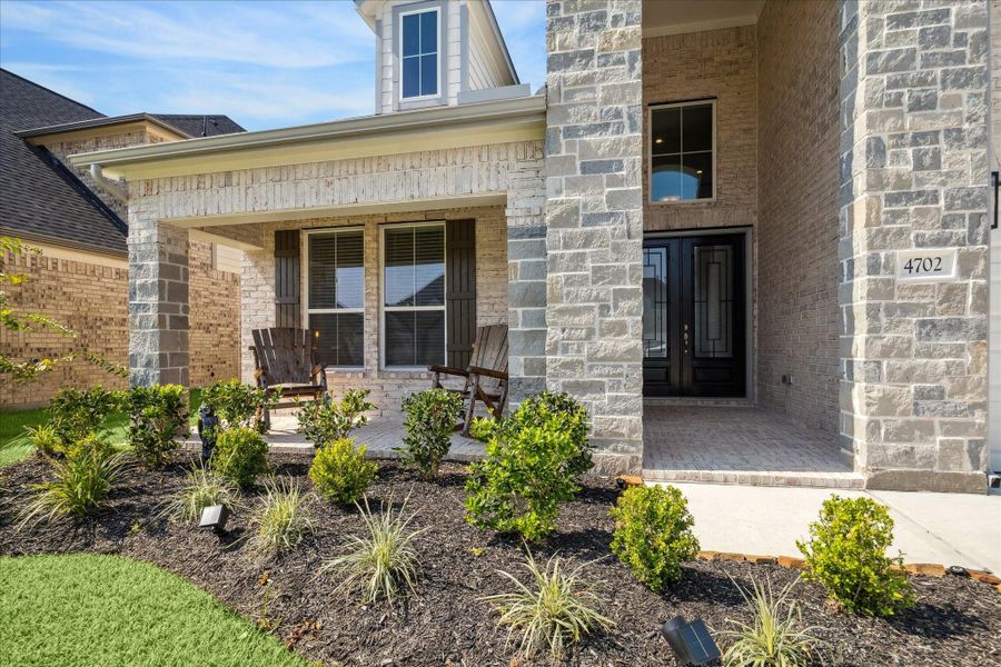 Charming covered front porch with stone accents and a welcoming double-door entry. Beautifully landscaped for great curb appeal. Charming covered front porch with stone accents and a welcoming double-door entry. Beautifully landscaped for great curb appeal.
