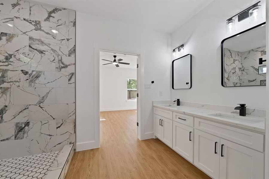 Full bathroom with double vanity, light wood-type flooring, a marble finish shower, and ceiling fan