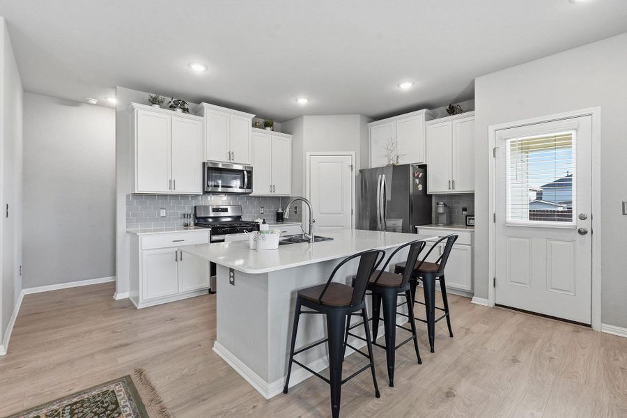 Kitchen with a kitchen breakfast bar, white cabinetry, stainless steel appliances, and recessed lighting Kitchen with a kitchen breakfast bar, white cabinetry, stainless steel appliances, and recessed lighting