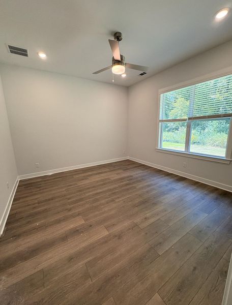 Wood-finish flooring, recessed lighting, ceiling fan with integrated light, and a large window
