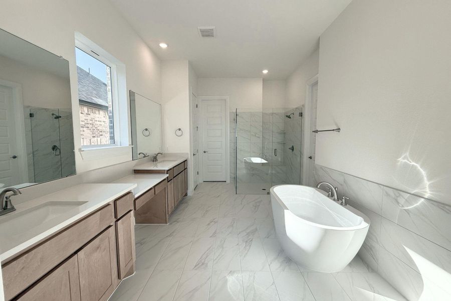 Full bathroom with two vanities, a marble finish shower, light marble finish floors, a freestanding bath, and tile walls