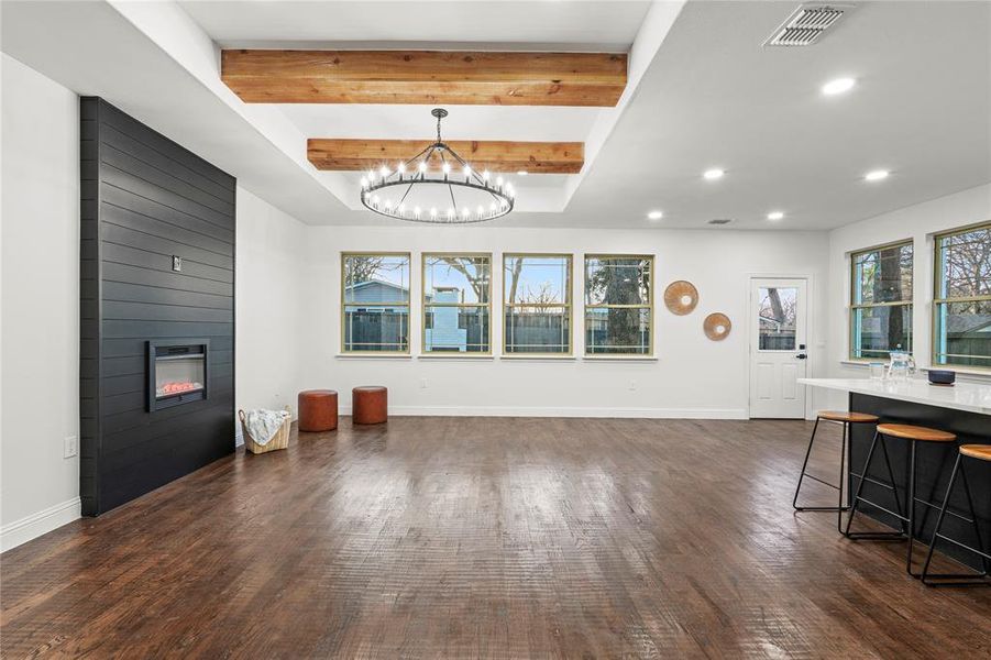 Living area with beam ceiling, dark wood-type flooring, a fireplace, and hanging lights