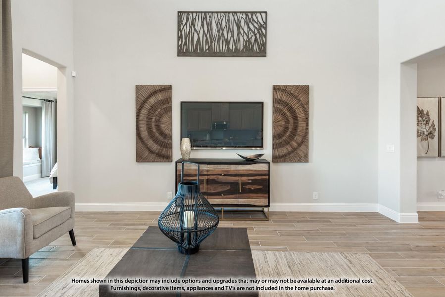 Living room with high ceilings, wall-mounted TV, wood dresser, and light tile floors with decorative wall art
