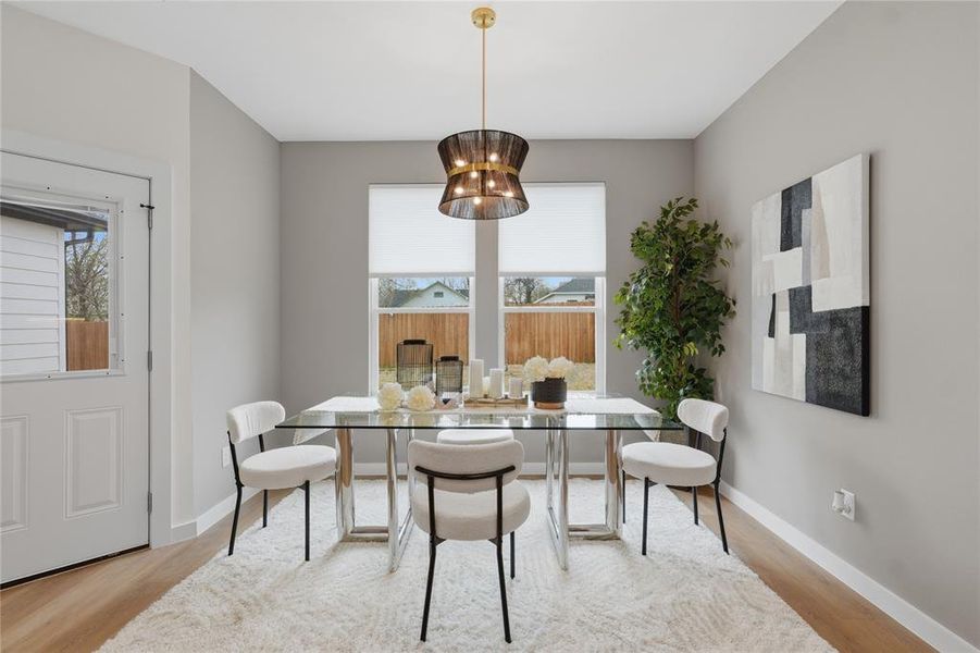 Dining area featuring light wood-style flooring, healthy amount of natural light, and suspended lighting Dining area featuring light wood-style flooring, healthy amount of natural light, and suspended lighting