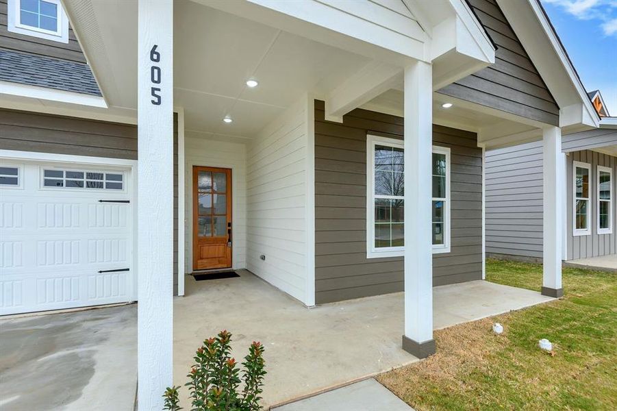 Doorway to property with a garage and roof with shingles
