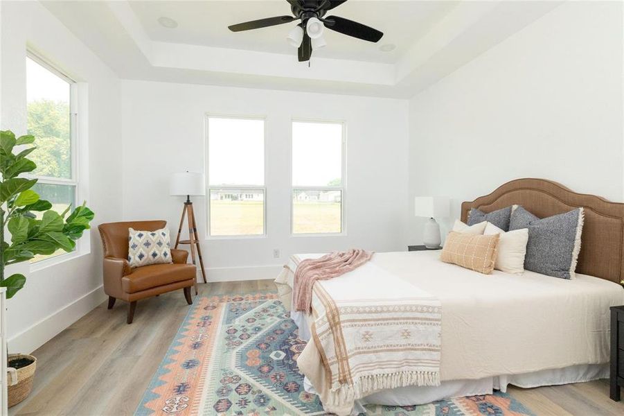 Bedroom featuring a tray ceiling, light hardwood / wood-style flooring, and ceiling fan