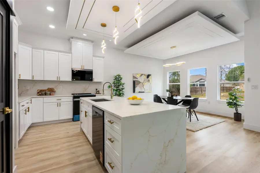 Kitchen with an island with sink, white cabinets, light stone counters, and decorative backsplash Kitchen with an island with sink, white cabinets, light stone counters, and decorative backsplash