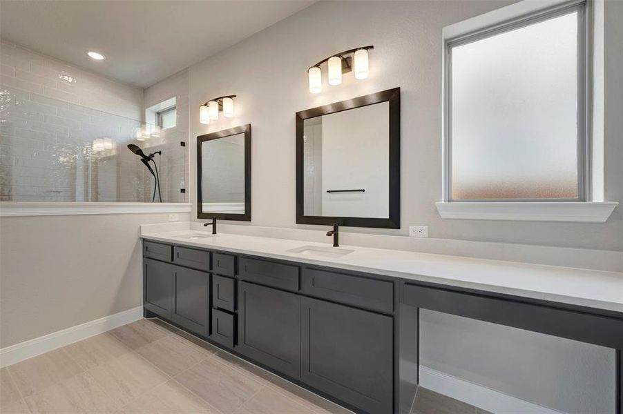 Dual vanity with dark cabinetry, white countertops, and matte black fixtures