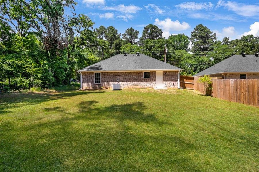 Rear view of house with brick siding, a patio, view of scattered trees, and roof with shingles Rear view of house with brick siding, a patio, view of scattered trees, and roof with shingles