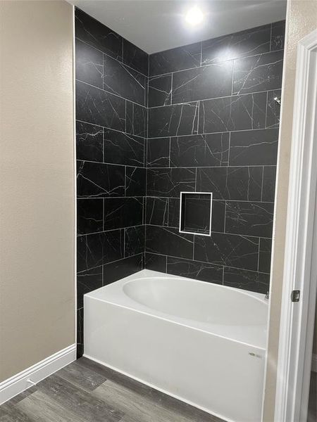 Full bathroom with wood finished floors, shower / bath combination, and baseboards
