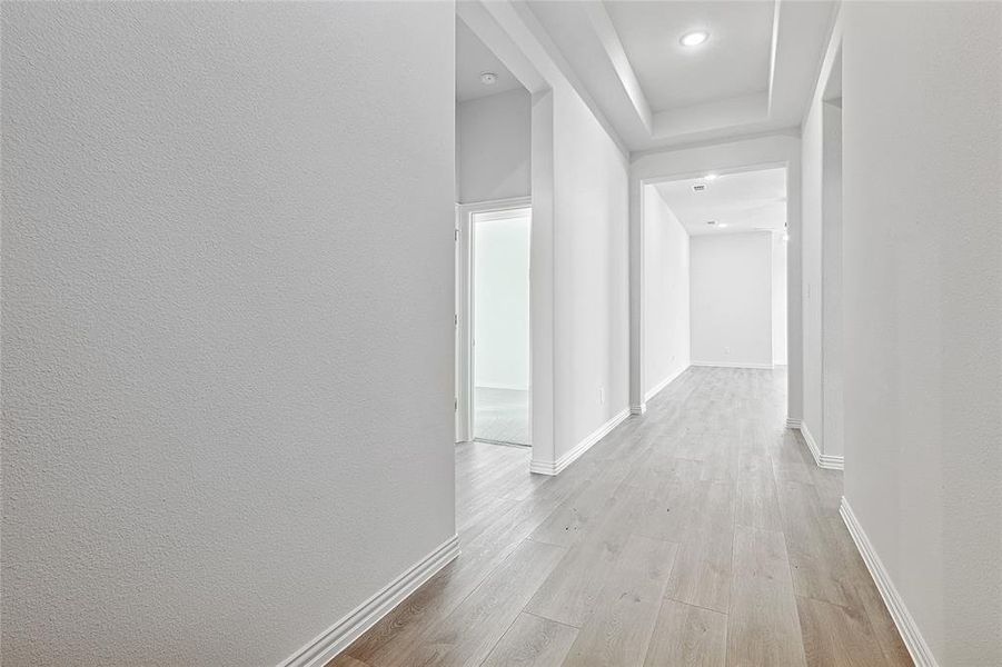 Corridor featuring light wood-type flooring and a textured wall