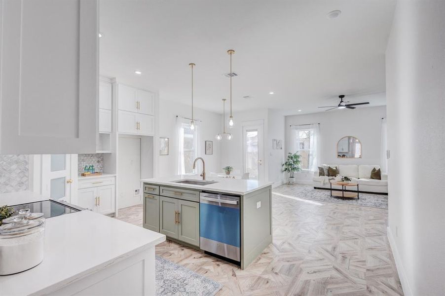 Kitchen with dishwasher, a kitchen island with sink, sink, hanging light fixtures, and ceiling fan