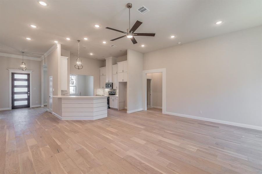 Kitchen featuring pendant lighting, light wood-type flooring, stainless steel appliances, and white cabinetry