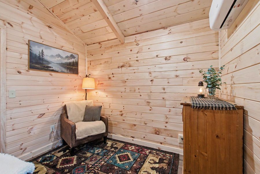 Living area featuring wooden walls, wood ceiling, a wall mounted air conditioner, and vaulted ceiling