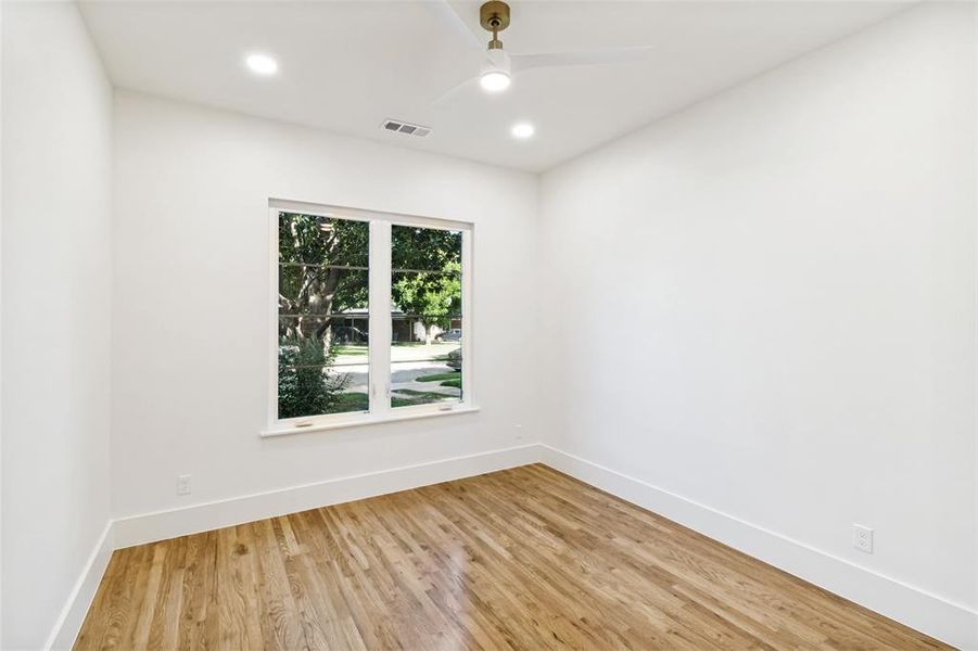 Bright interior space featuring a double window, wood-finish flooring, recessed lighting, a ceiling fan with integrated light, and crisp white walls with baseboards Bright interior space featuring a double window, wood-finish flooring, recessed lighting, a ceiling fan with integrated light, and crisp white walls with baseboards
