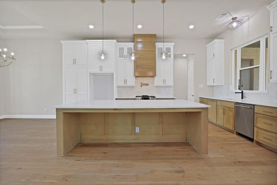 Kitchen with light wood-type flooring, a large island, stainless steel dishwasher, and white cabinetry