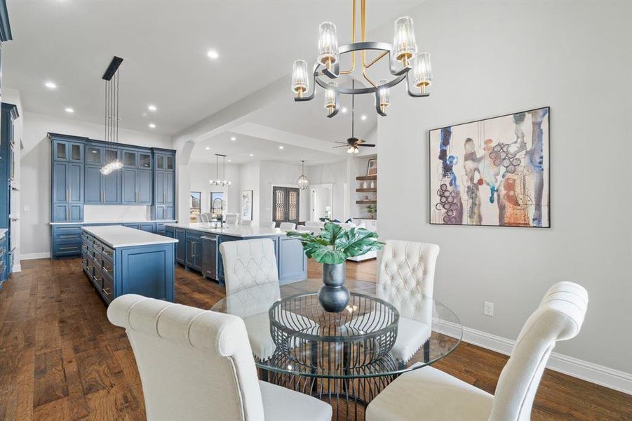 Dining space featuring ceiling fan with notable chandelier, sink, and dark hardwood / wood-style floors