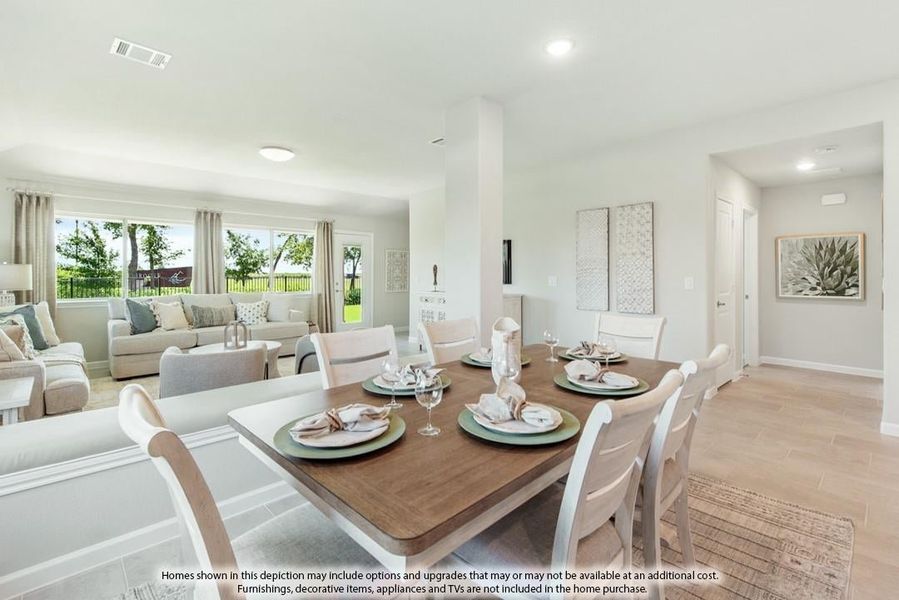 Open-concept dining area with wood table and white chairs, flowing into a bright living room with large windows.