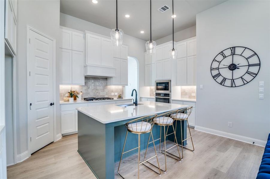 Kitchen with white cabinetry, sink, and an island with sink