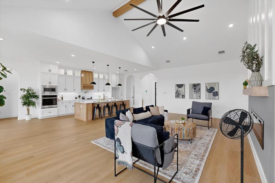 Living room featuring a ceiling fan, recessed lighting, arched walkways, high vaulted ceiling, and beam ceiling