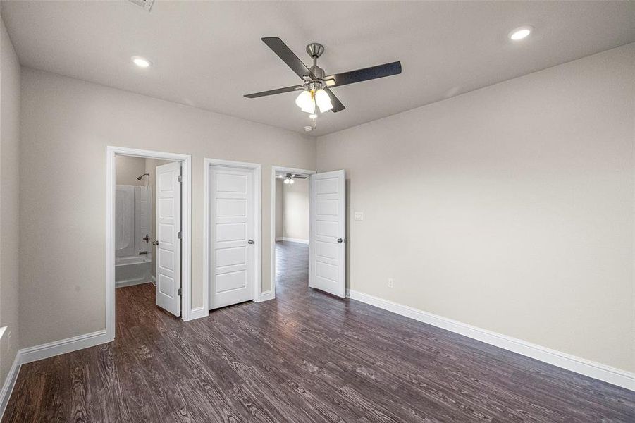 Unfurnished bedroom featuring dark hardwood / wood-style floors, ceiling fan, and ensuite bathroom