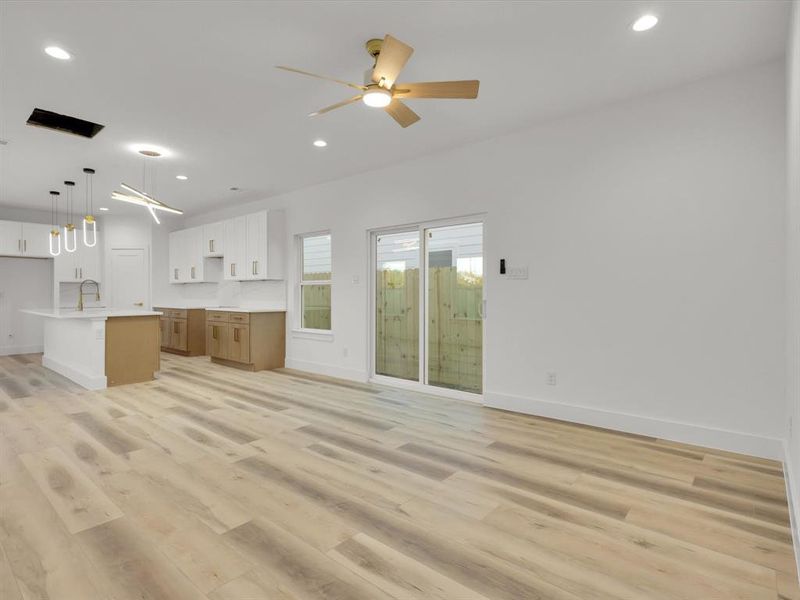 Unfurnished living room with ceiling fan, light hardwood / wood-style flooring, and sink