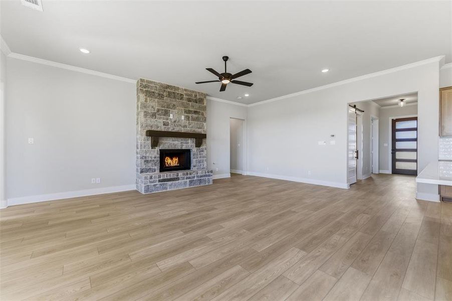 Unfurnished living room with light wood-style floors, a fireplace, recessed lighting, ornamental molding, and ceiling fan