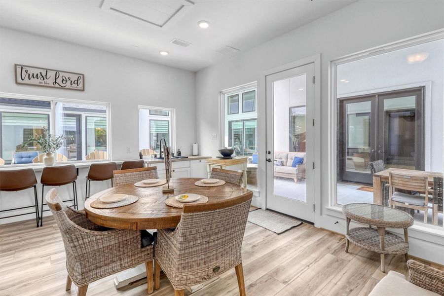 Casita dining and living area combination is light and bright, with recessed lighting, and walls of windows. The same wide plank flooring and attention to detail in the home is carried over into the casita.