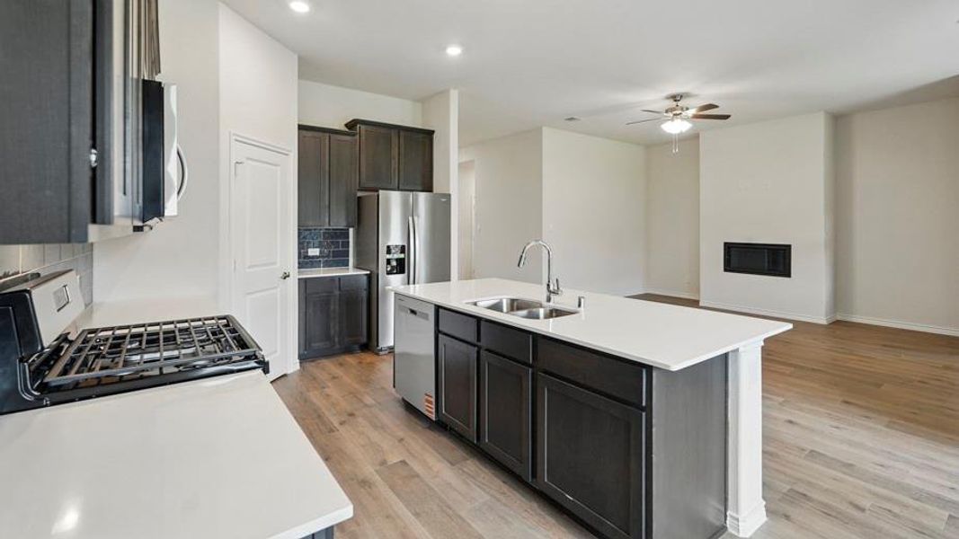 Open-concept living space with a kitchen island featuring a double-basin sink and stainless steel appliances Open-concept living space with a kitchen island featuring a double-basin sink and stainless steel appliances