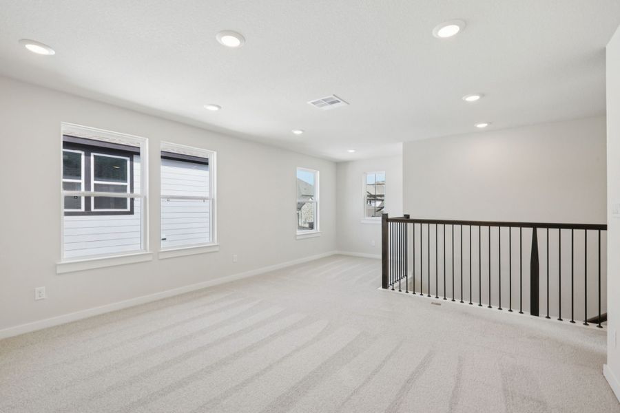A room with a wood railing and a white wall with a black railing.