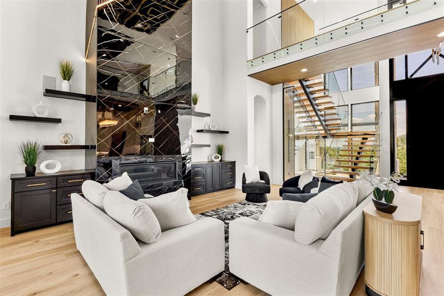Soaring two-story living space featuring a mirrored accent wall with an integrated fireplace
