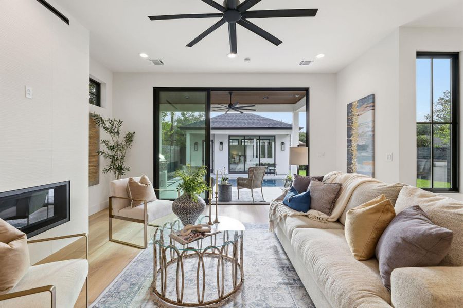 Living room featuring a glass covered fireplace, wood finished floors, recessed lighting, and ceiling fan
