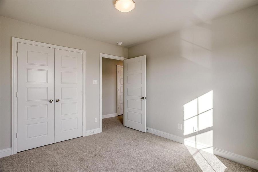 Unfurnished bedroom with light carpet and a closet