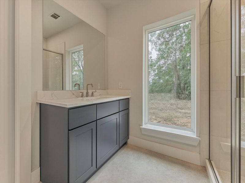 Sleek Casita bathroom showcasing a modern vanity with quartz surfaces, expansive mirror, and a serene picture window that fills the space with natural light—simple, sophisticated, and beautifully designed.