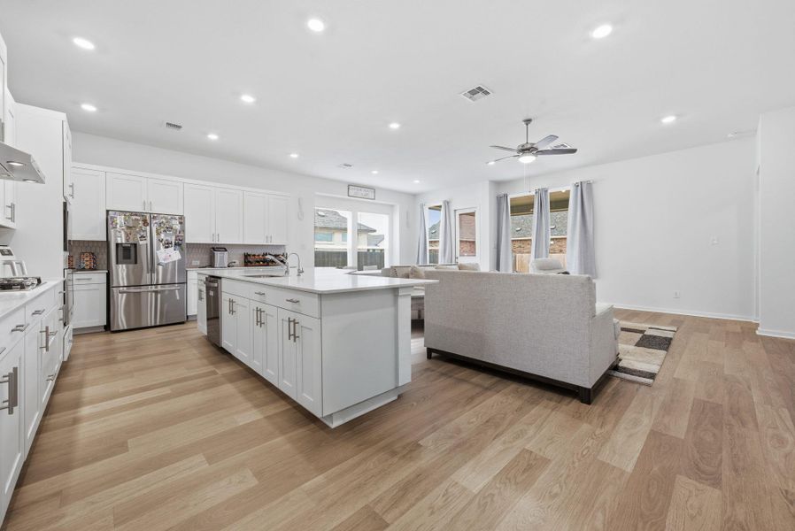 Kitchen featuring a center island with sink, white cabinets, stainless steel appliances, light wood-style flooring, and recessed lighting