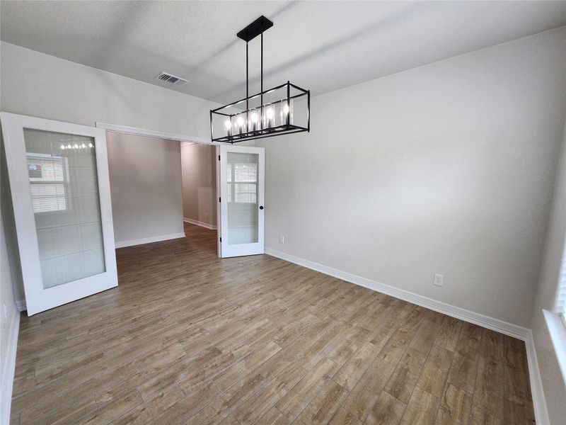 A well-lit room featuring elegant French doors and sophisticated wood-look tile flooring. A well-lit room featuring elegant French doors and sophisticated wood-look tile flooring.