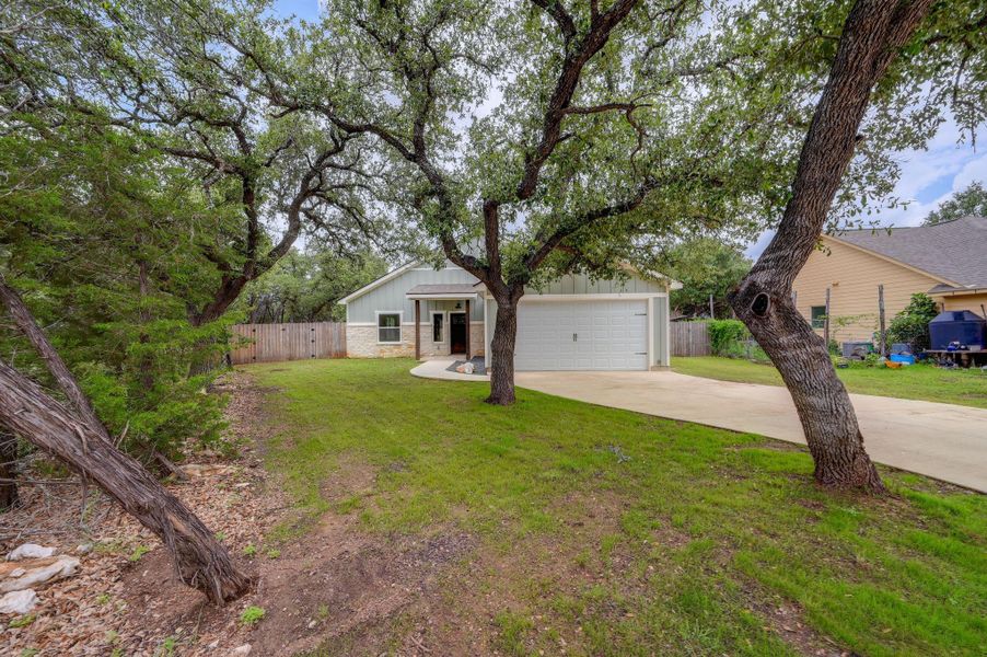 A welcoming residence featuring a neat lawn and driveway, nestled among established trees and natural landscaping. A welcoming residence featuring a neat lawn and driveway, nestled among established trees and natural landscaping.