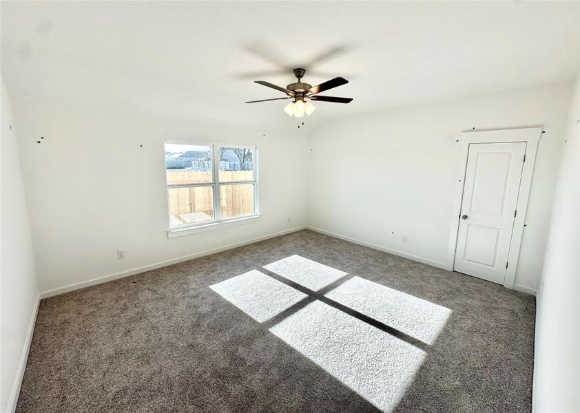 Empty room with a ceiling fan and carpet flooring