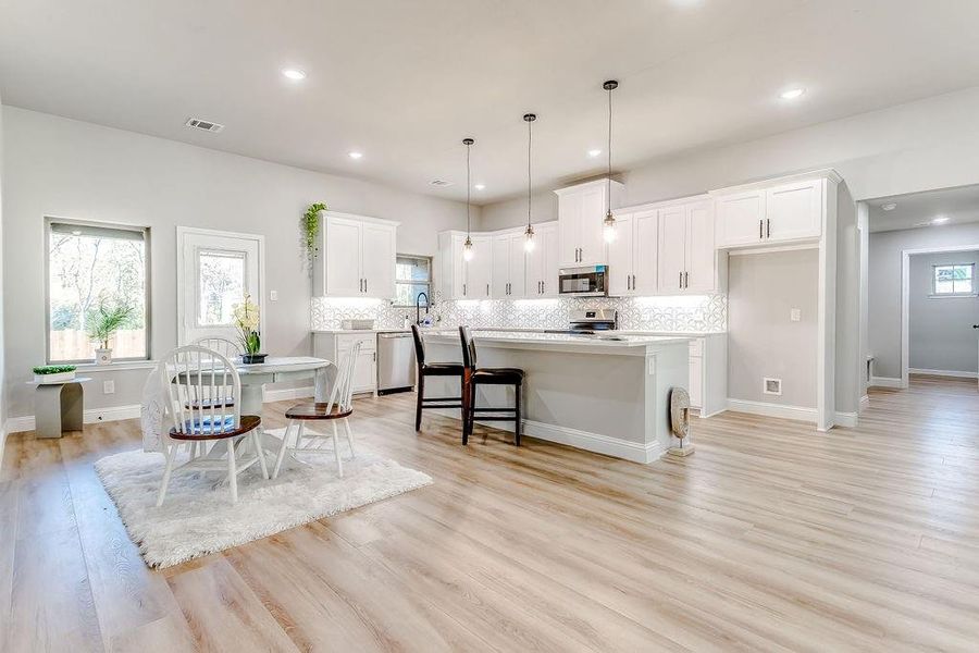 Kitchen with backsplash, white cabinets, a kitchen island, and stainless steel appliances