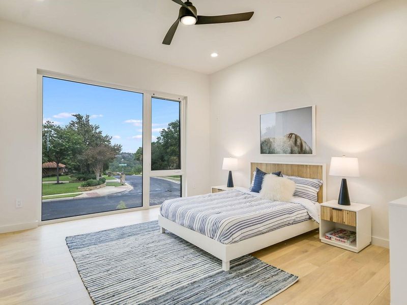 A tranquil sleeping space boasts tall windows, offering scenic street and nature views. A tranquil sleeping space boasts tall windows, offering scenic street and nature views.