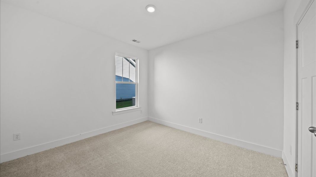 Highly functional bedroom with large windows, carpeted flooring, and tasteful finishes throughout