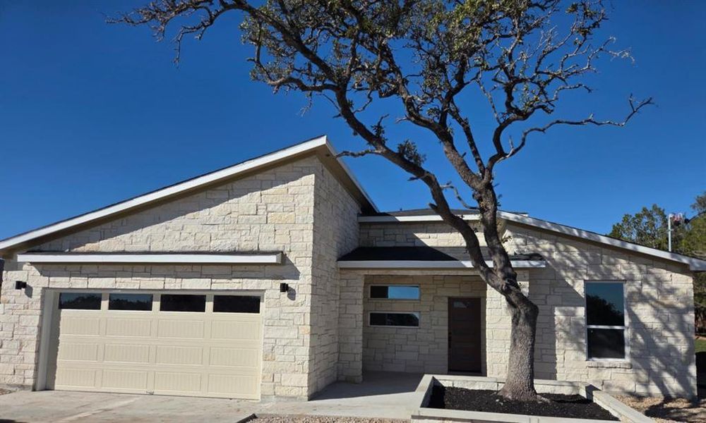 View of front facade with an attached garage, stone siding, and driveway View of front facade with an attached garage, stone siding, and driveway