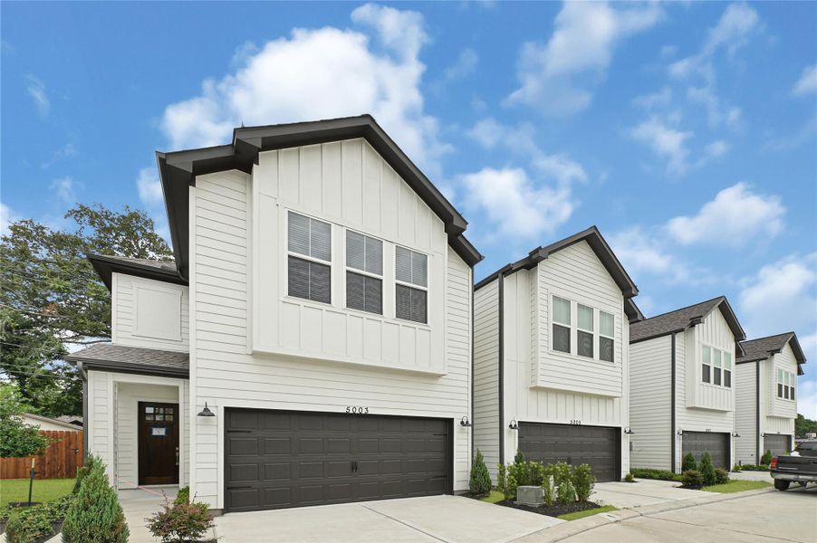 Modern two-story homes with sleek white exteriors and dark garage doors, set in a neat, landscaped neighborhood under a clear blue sky. Modern two-story homes with sleek white exteriors and dark garage doors, set in a neat, landscaped neighborhood under a clear blue sky.