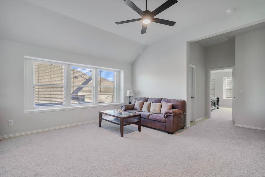 Living room featuring light carpet, a ceiling fan, and lofted ceiling