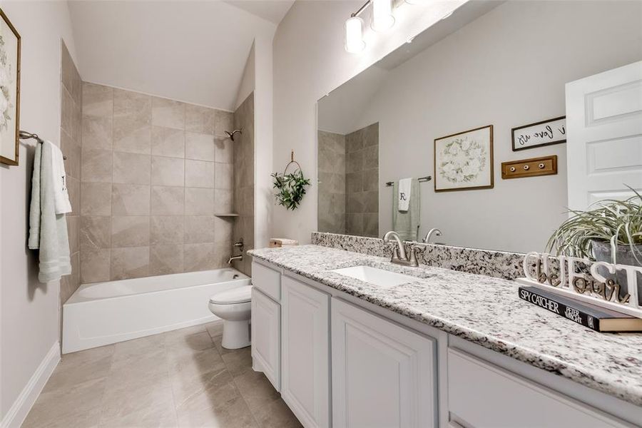 Upstairs full bathroom with quartz dual vanity and tiled shower/tub.(Home has different colored counters than in photo.)