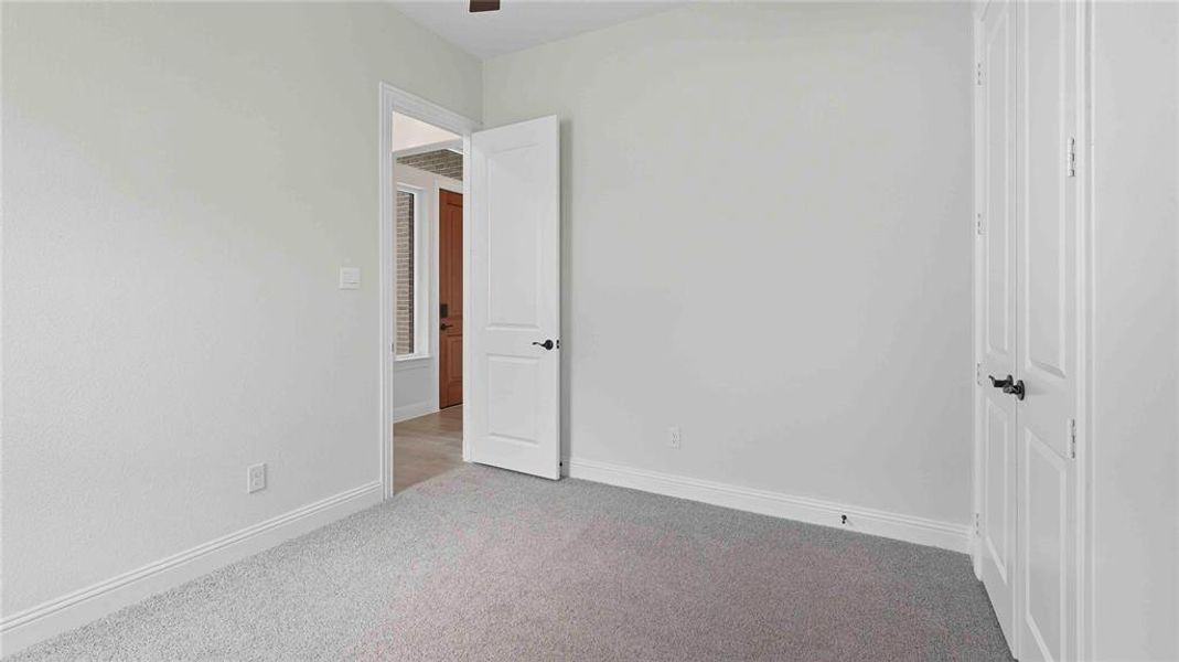 Carpeted room featuring light neutral wall tones, white trim, and a paneled door with dark hardware