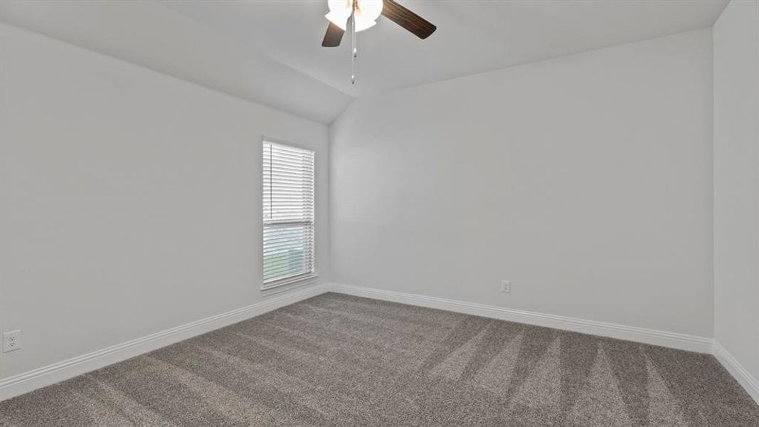 Carpeted spare room with a ceiling fan and lofted ceiling