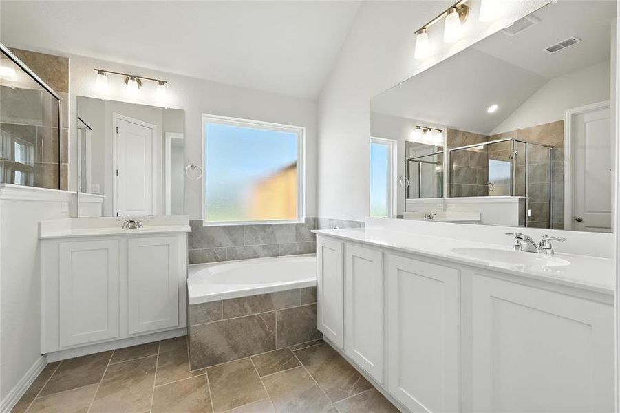 Full bathroom featuring lofted ceiling, two vanities, a garden tub, and a shower stall Full bathroom featuring lofted ceiling, two vanities, a garden tub, and a shower stall